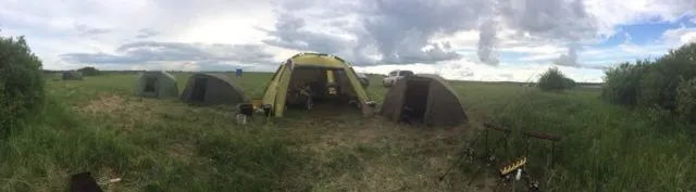 Лагерь карпятников с палатками и раскладушками на берегу водоема для ловли карпа