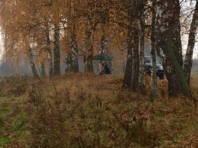 Рыболов под зонтом в осеннем лесу на карповой рыбалке с комфортным оборудованием
