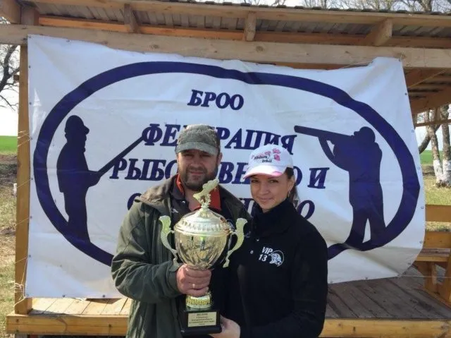 Победители турнира по карпфишингу с кубком на фоне баннера федерации рыболовства