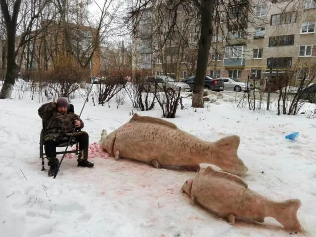 Рыболов с трофейными карпами на снегу в городском дворе зимой