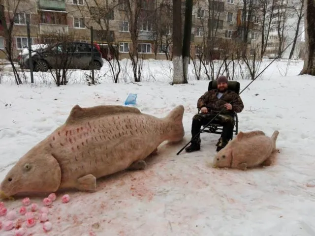 Рыбак с огромным трофейным карпом из снега на зимней рыбалке